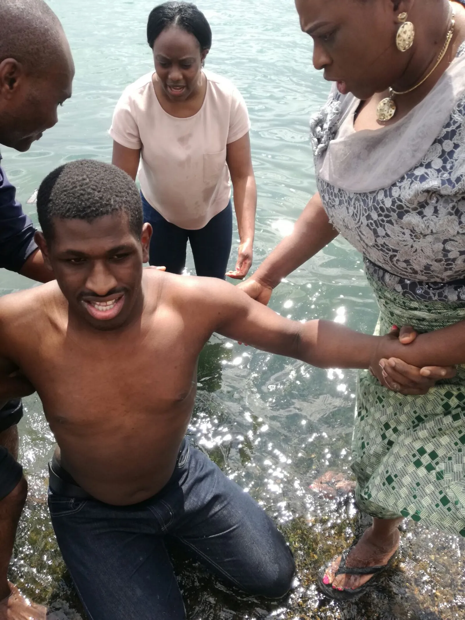 Baptism by immersion of a man by a man and two woman