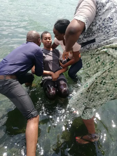 Baptism by immersion of a woman by a man and two woman