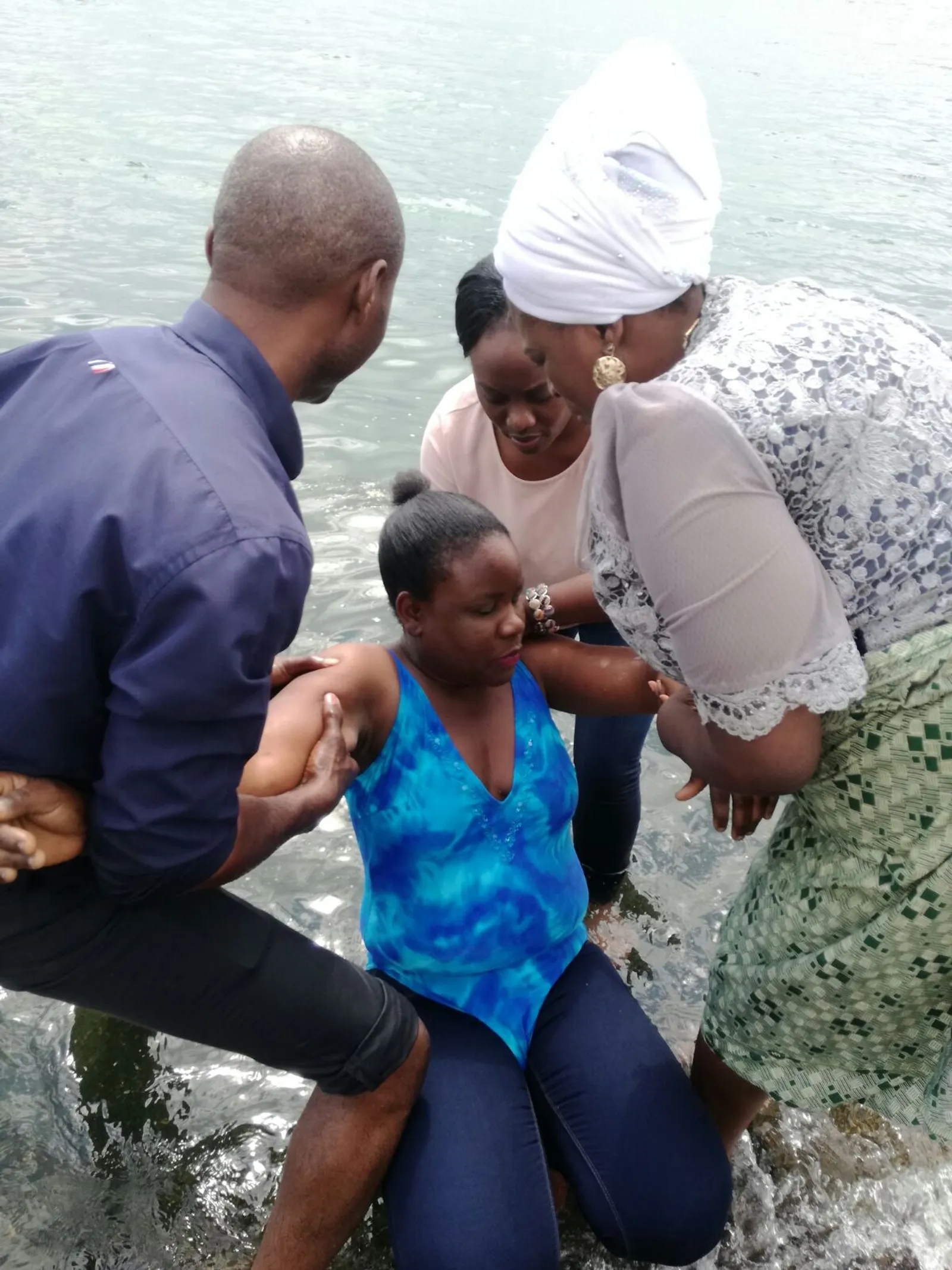 Baptism by immersion of a woman by a man and two woman